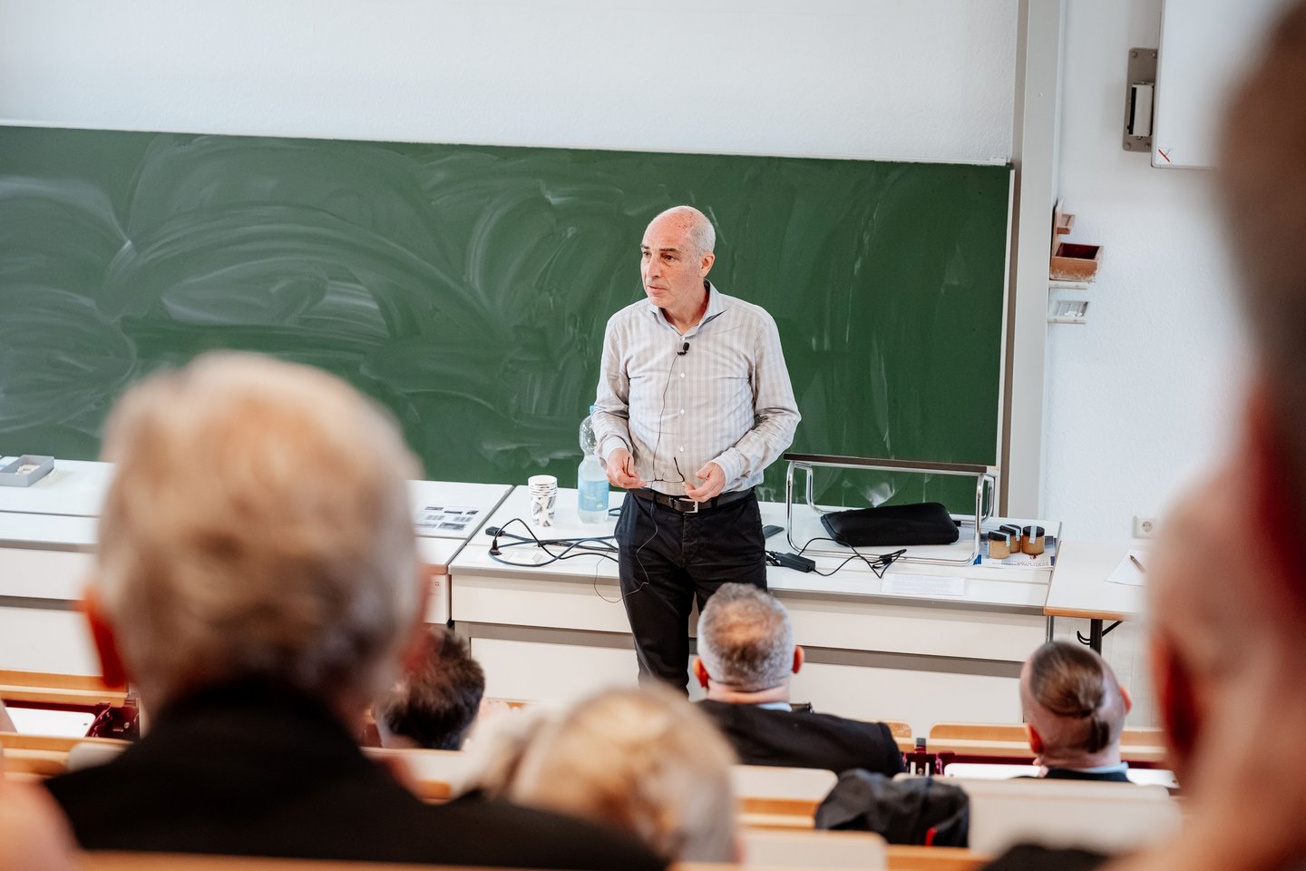 Professor steht in Hörsaal vor Gästen und begrüßt