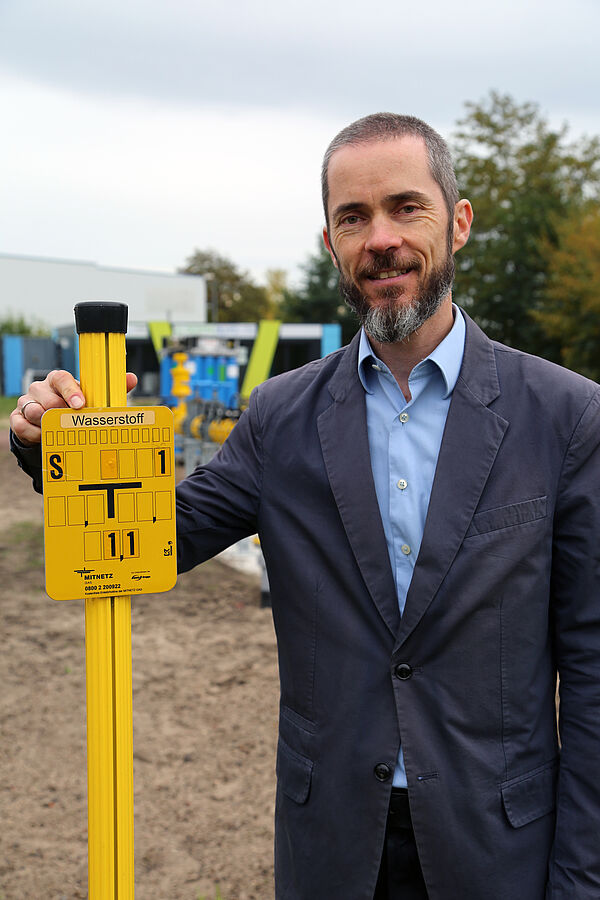 ein Mann steht nehem einem Gasschild mit der Aufschrift Wasserstoff