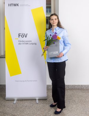 Frau in dunkler Hose vor Plakat