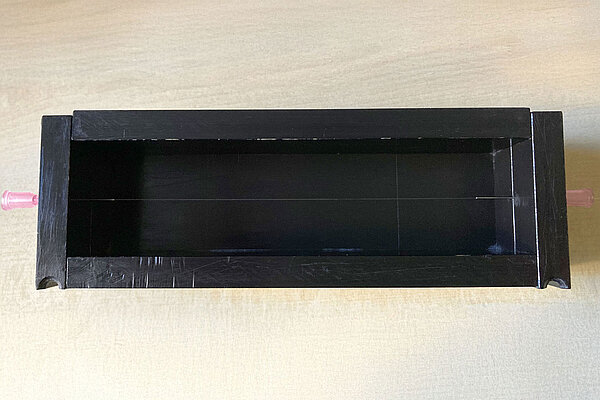 ein schwarzer Kasten mit einer gespannten Glasfaser