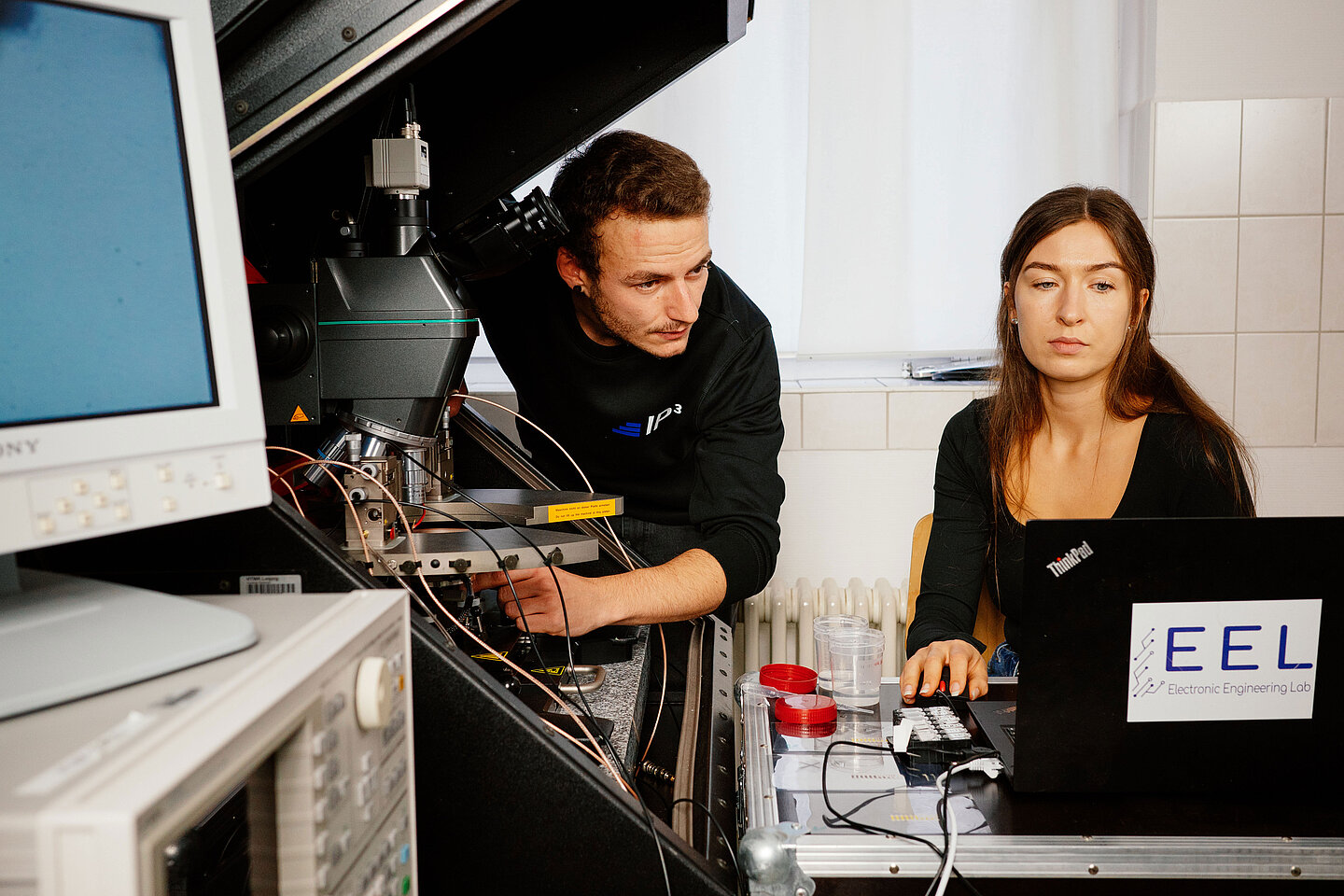 1. Platz: Florian Muschka ∙ Anika Mühl ∙ Sammy Schließer: "Transistoren im Tampondruck" ein Mann und eine Frau messen Transistoren und blicken in einen Computer