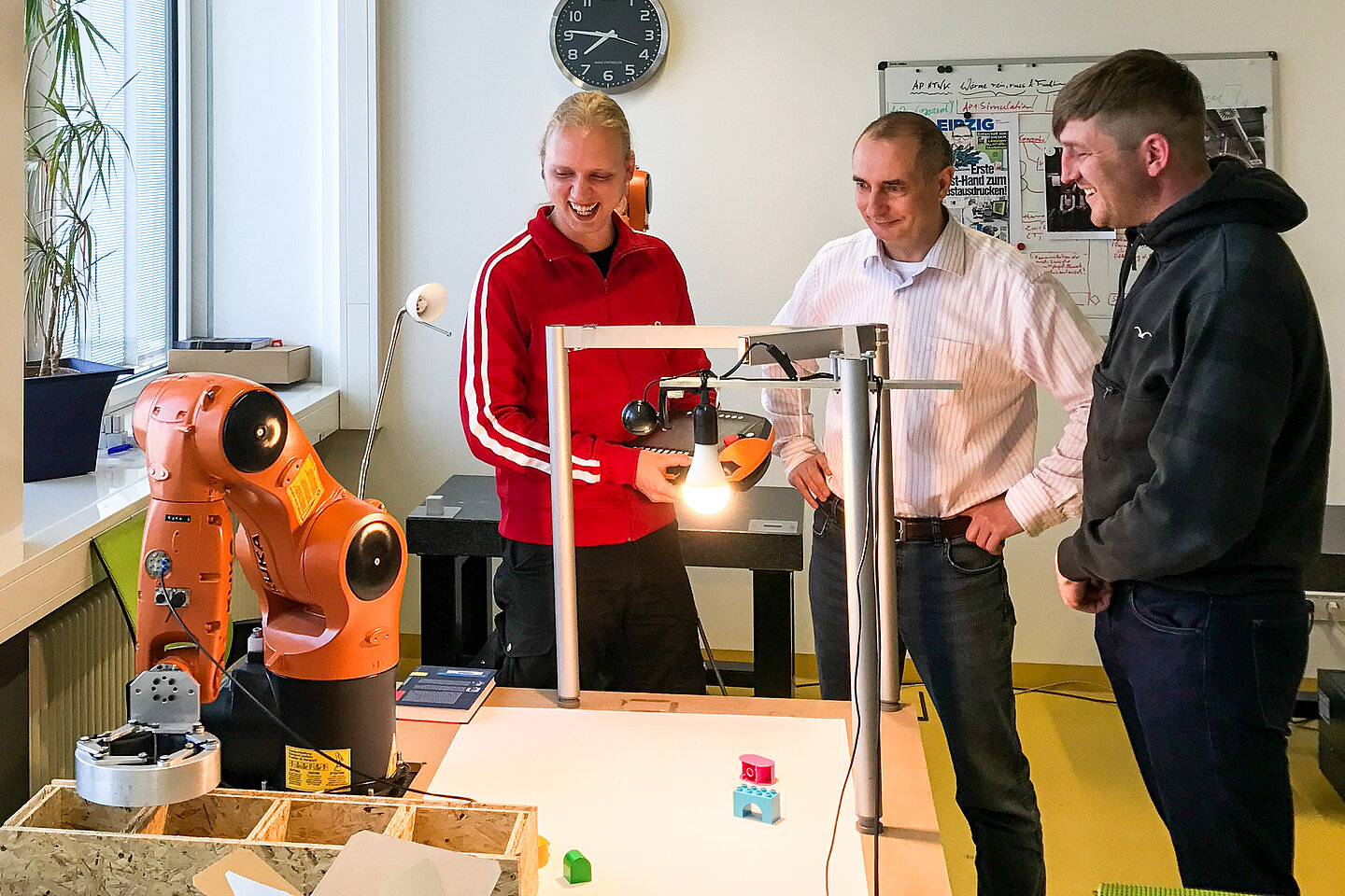 Prof. Detlef Riemer (Mitte) mit Frank Schmidt (rechts) und Robert Wedermann von Gründerteam Recovics im Mechatronik-Labor der HTWK Leipzig Drei Männer mit einem Roboter im Labor