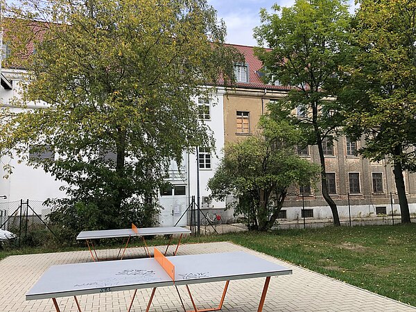 Tischtennisplatten in Hof mit Gebäuden dahinter